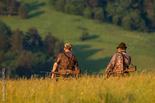 Obraz na plátně Two hunters going for an evening hunting in the mountains