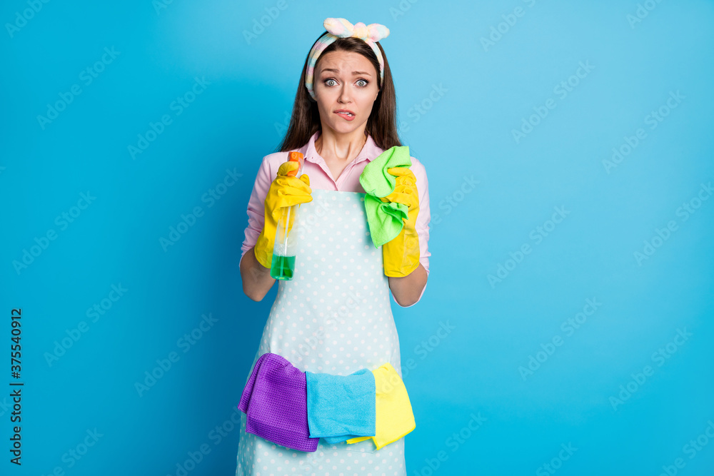 Portrait of her she nice attractive pretty cute worried maid holding in hands tools sanitary hygiene disinfectant biting lip isolated over bright vivid shine vibrant blue color background Portrait of her she nice attractive pretty cute worried maid holding in hands tools sanitary hygiene disinfectant biting lip isolated over bright vivid shine vibrant blue color background