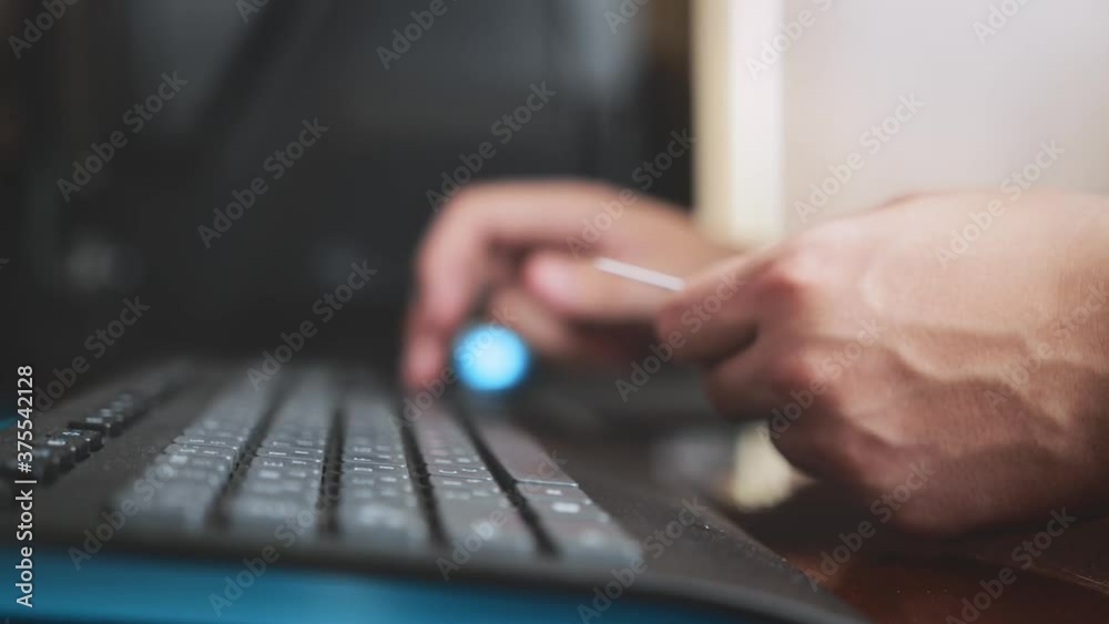 a cinematic picture of male hands and fingers filling out payment details. the programmer works from home. guy is shopping online. a man enters data from a credit card on a personal computer.