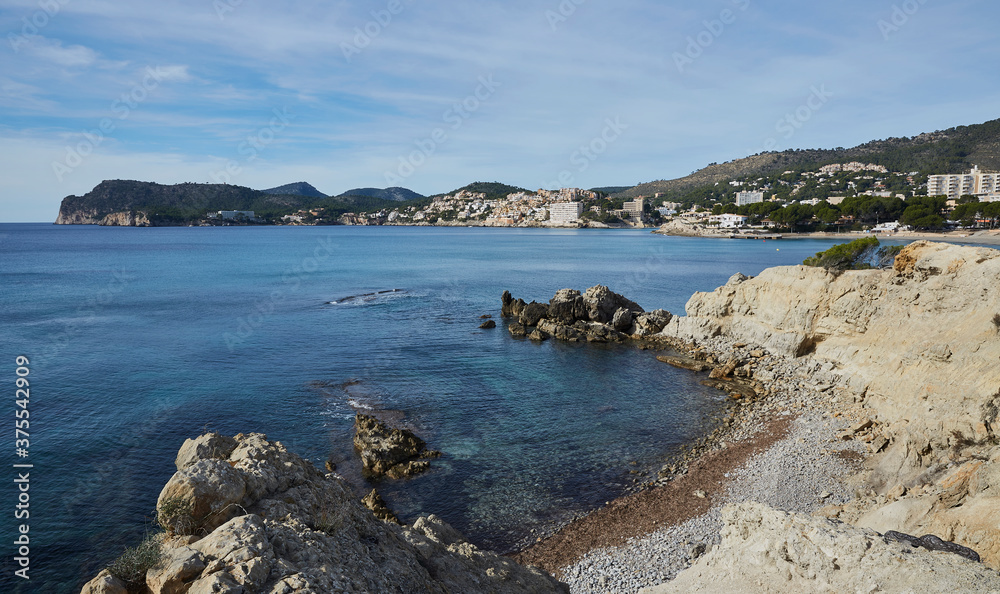 Fototapeta premium Calo de Sa Romana, a rocky beach some the size of a melon, in the background the Mirador de Cap Andritxol. Peguera, municipality of Calviá, Mallorca