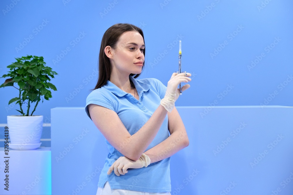 Young beautiful woman nurse with syringe, female doctor in uniform looking at the camera Young beautiful woman nurse with syringe, female doctor in uniform looking at the camera