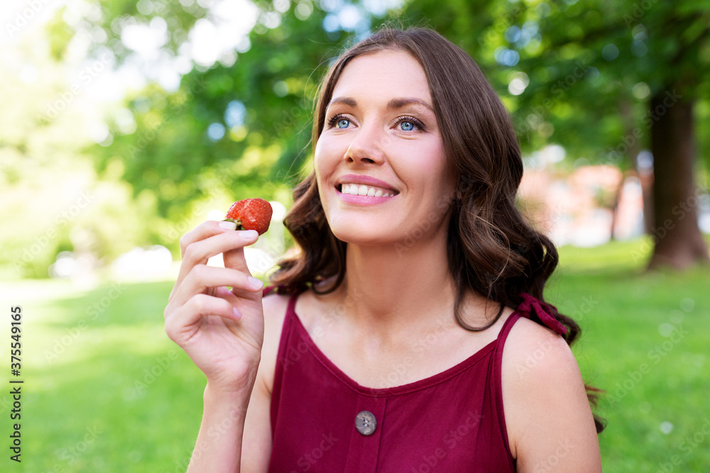 leisure and people concept - portrait of happy woman eating strawberry at summer park leisure and people concept - portrait of happy woman eating strawberry at summer park