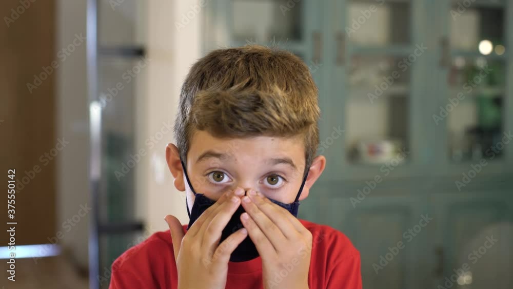 Caucasian boy puts on a protective mask at home looking at camera. Concept new rules, new normality during Coronavirus, COVID-19. Caucasian boy puts on a protective mask at home looking at camera. Concept new rules, new normality during Coronavirus, COVID-19.