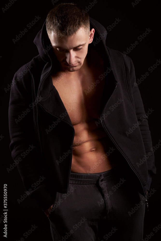 Bodybuilder standing in black hoodie. Studio shot. Isolated