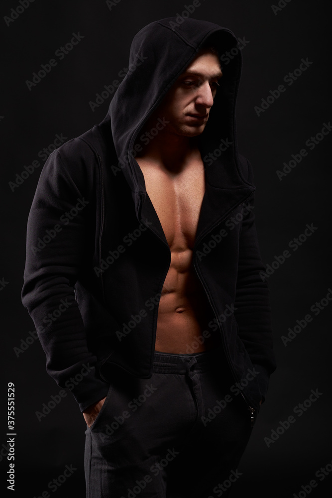 Bodybuilder standing in black hoodie. Studio shot. Isolated