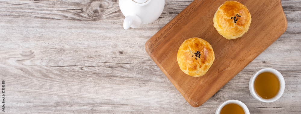 Moon cake yolk pastry, mooncake for Mid-Autumn Festival holiday, top view design concept on bright wooden table with copy space, flat lay, overhead shot