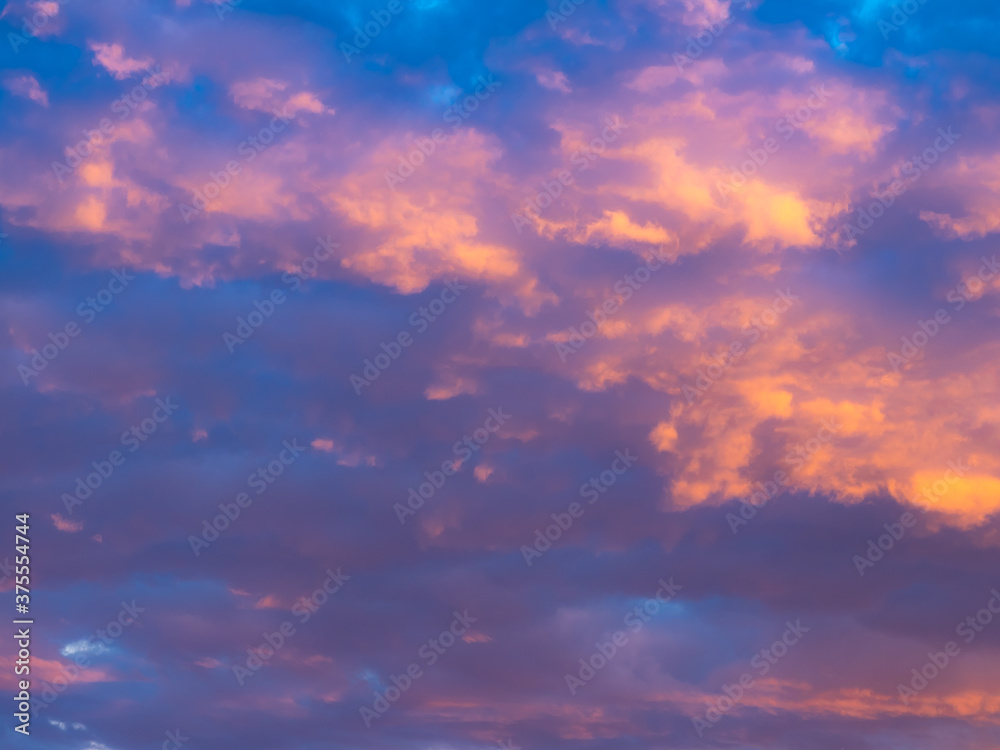 A colorful sky full of pink, blue and orange colors. Contrasting clouds shimmering in different colors at sunset, illuminated by the setting sun. Bright saturated natural background.