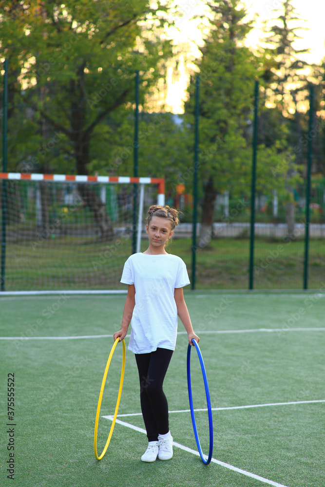 Φωτογραφία girl is engaged in gymnastics with hoops on the sports field.