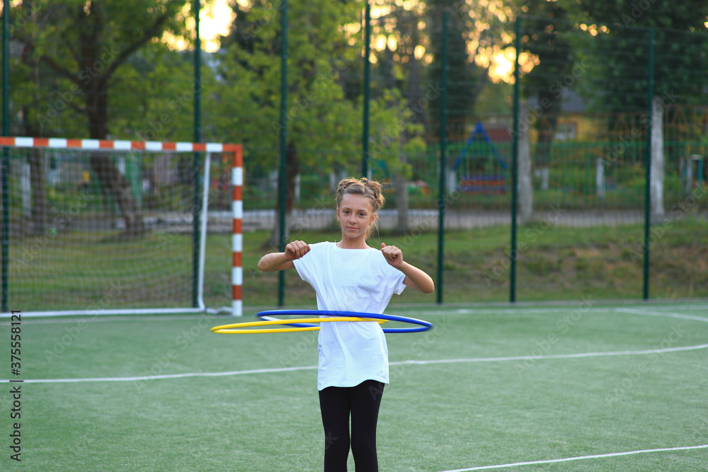girl is engaged in gymnastics with hoops on the sports field. girl is engaged in gymnastics with hoops on the sports field.