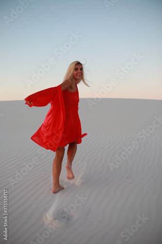 young woman in red dress walking on the beach
