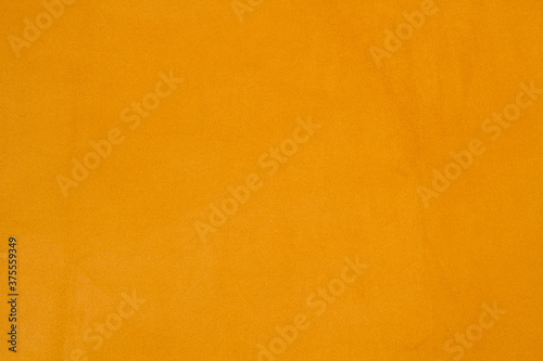 Ocher matte background of suede fabric, closeup. Velvet texture of seamless yellow leather.