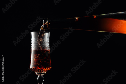 Aged golden fortified wine from the antique bottle being poured into a crystal glass. photo