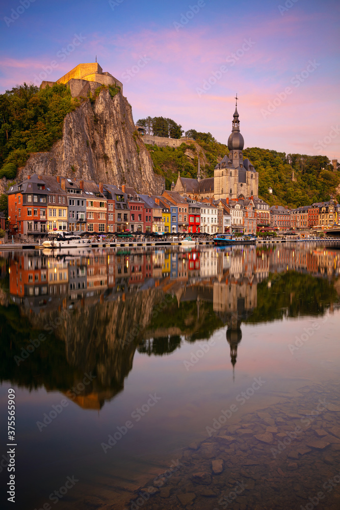 Dinant, Belgium. Cityscape image of beautiful historical city of Dinant with the reflection of the city in the Meuse River at summer sunset.