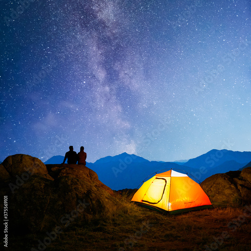 Photography Young Couple Sitting on the Rock near Illuminated Tent and Watching the Bright M