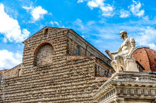 Façade of the church of St Lawrence (Basilica di San Lorenzo), one of the oldest in Florence redesigned by Brunelleschi in the 15th century, and the marble statue of Giovanni dalle Bande Nere.