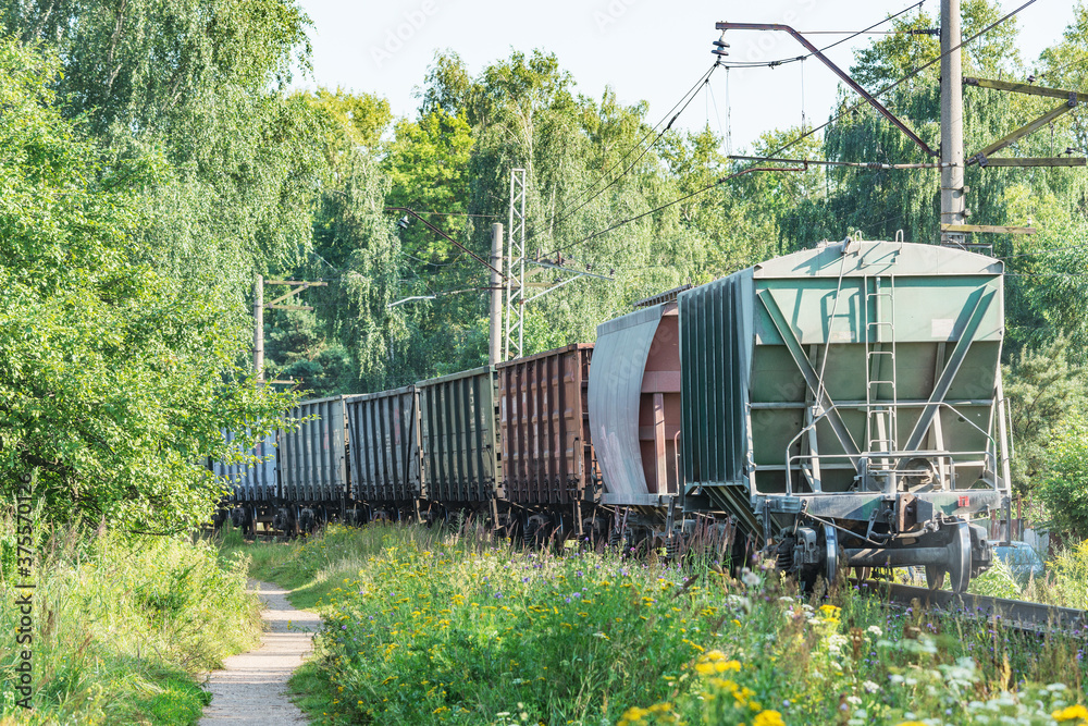 Freight train moves by the forest at summer day time. Freight train moves by the forest at summer day time.