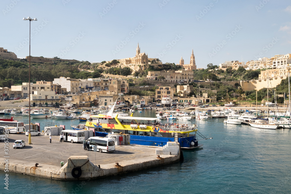 The ferry from Malta to Gozo island goes to the picturesque harbor of Mgarr port where the luxury yachts and traditional fishing boats are staying