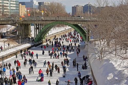 Many people ice skating on the frozen rideau canal on a cold winter day during the winterlude festival in downtown Ottawa, capital of Canada photo