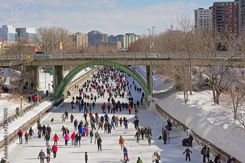 Many people ice skating on the frozen rideau canal on a cold winter day during the winterlude festival in downtown Ottawa, capital of Canada photo
