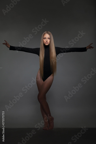 Beautiful girl teenager blonde in a black bodysuit in the studio