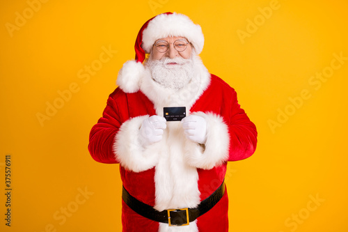 Photo of jolly holly fairy santa claus hold credit card recommend bank earnings money savings for x-mas christmas buyer gift present wear cap headwear isolated bright shine color background