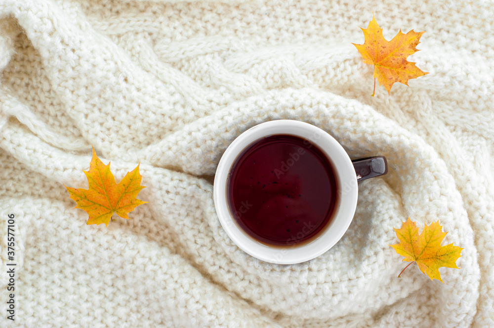 A warming cup of tea in a white knitted plaid. A warming cup of tea in a white knitted plaid.