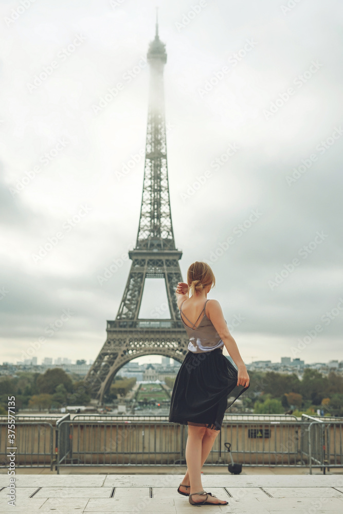 Girl in a black skirt near the Eiffel tower in Paris. Back view