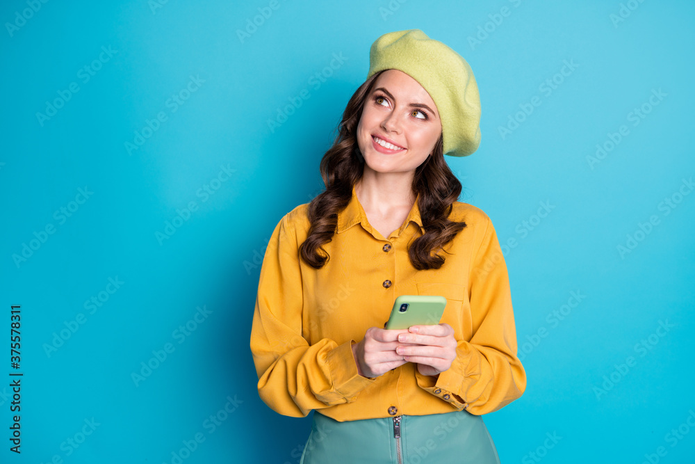 Photo of inspired girl use smartphone look copyspace plan social network feedback chatting chilling wear yellow headwear isolated over blue color background Photo of inspired girl use smartphone look copyspace plan social network feedback chatting chilling wear yellow headwear isolated over blue color background