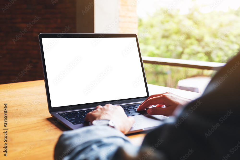 Mockup image of a woman using and typing on laptop computer keyboard with blank white desktop screen on wooden table Mockup image of a woman using and typing on laptop computer keyboard with blank white desktop screen on wooden table
