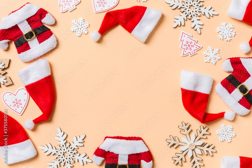 Obraz premium Top view of Christmas decorations and Santa hats on orange background. Happy holiday concept with copy space