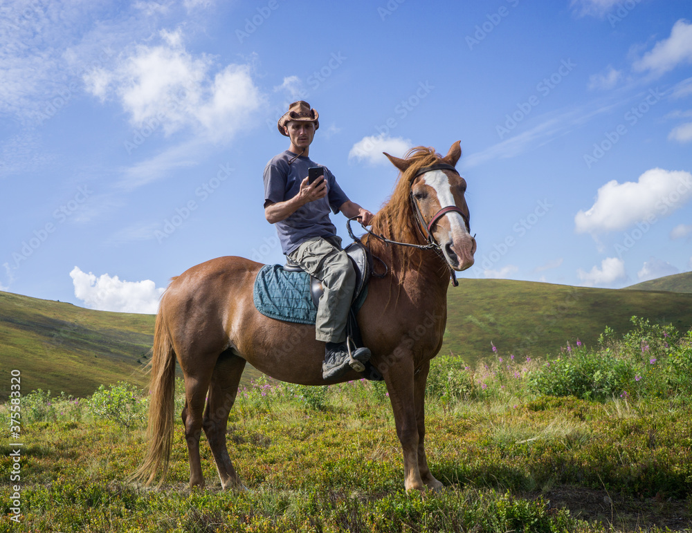 A rider in a wide-brimmed cowboy hat on a horse against a blue sky. A rider in a wide-brimmed cowboy hat on a horse against a blue sky.