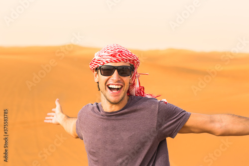 Photography Happy young male tourist having fun enjoying a safari trip in the Arabian desert sand dunes wearing a local headwear