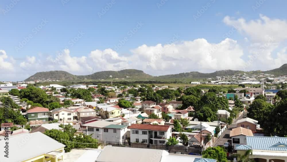 Aerial shot of Independence Square in Basseterre, St. Kitts and Nevis. Drone flying backwards from residential houses area, over the cathedral and revealing trees and fountain Aerial shot of Independence Square in Basseterre, St. Kitts and Nevis. Drone flying backwards from residential houses area, over the cathedral and revealing trees and fountain