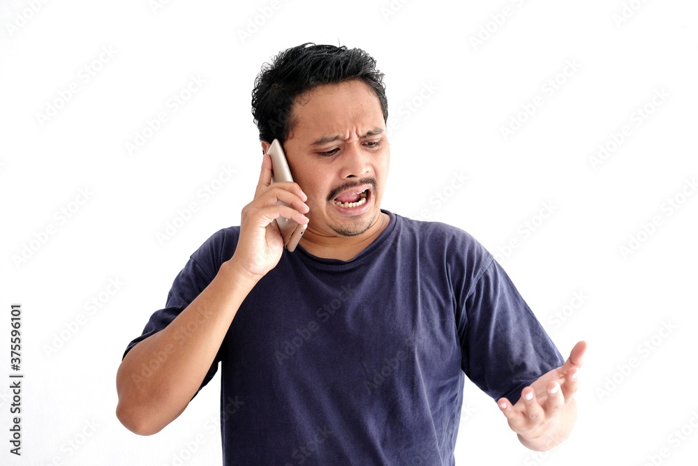 Asian man talking on phone with angry expression Asian man talking on phone with angry expression
