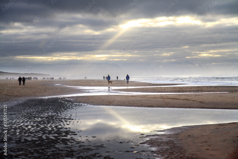 Sunbeam piercing through the clouds at low tide on the beach
