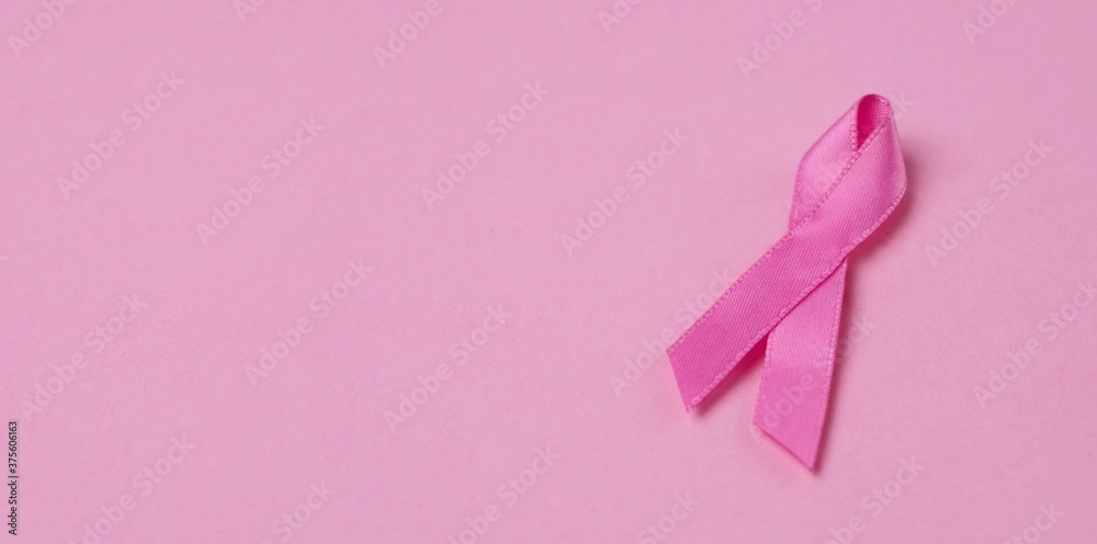 Pink ribbon breast cancer awareness symbol on pink background. Panoramic image with copy space.