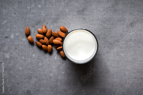 Almond milk in a glass with almond ingredients on table