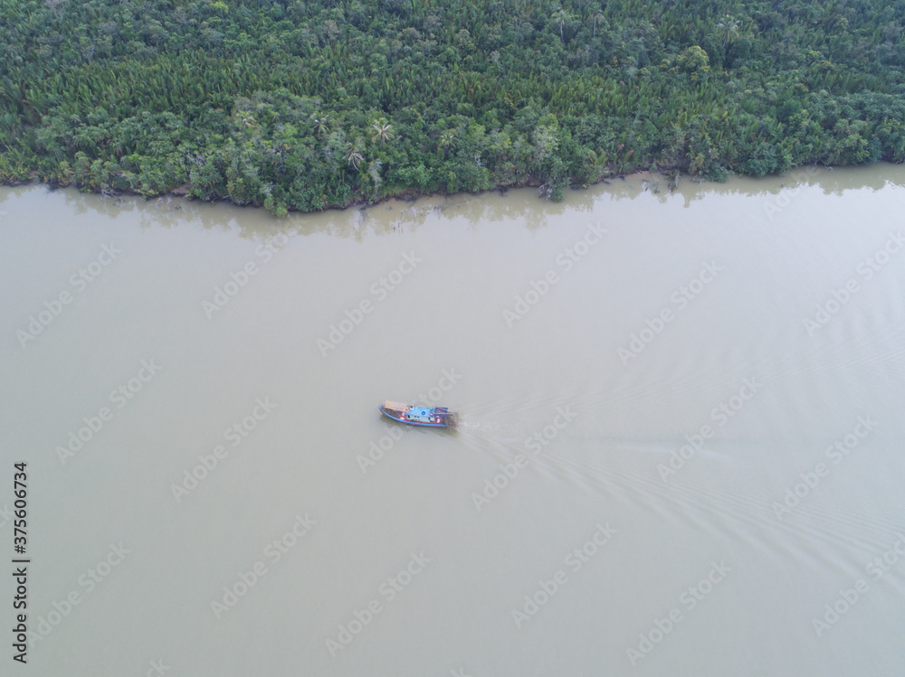 Obraz premium Aerial view. Boat sailing across river with rainforest at river bank