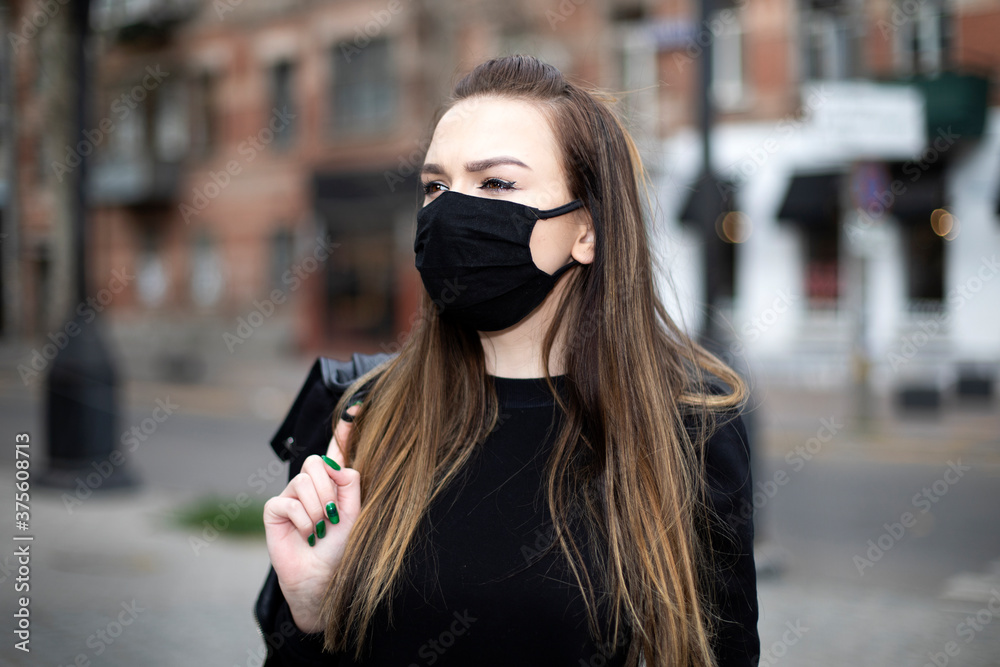 girl with a black mask on her face walks around the city