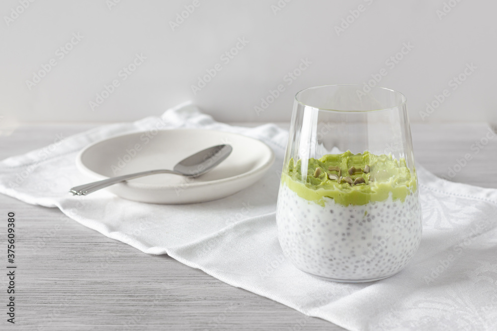 Healthy chia pudding with avocado, spoon and plate on the napkin. White background. Healthy breakfast and food concept.