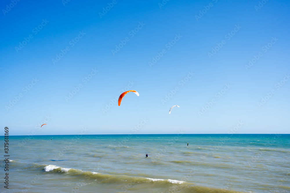 Beautiful kiteboarding surfing with golden sand sea water. Kite in the air on the beach, sunny outdoors background. Beautiful kiteboarding surfing with golden sand sea water. Kite in the air on the beach, sunny outdoors background.