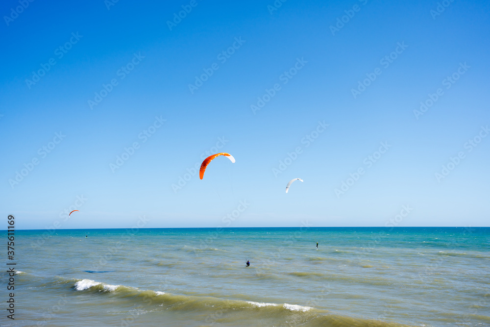 Beautiful kiteboarding surfing with golden sand sea water. Kite in the air on the beach, sunny outdoors background.