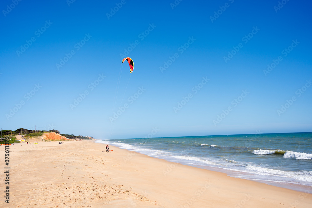 Beautiful kiteboarding surfing with golden sand sea water. Kite in the air on the beach, sunny outdoors background. Beautiful kiteboarding surfing with golden sand sea water. Kite in the air on the beach, sunny outdoors background.