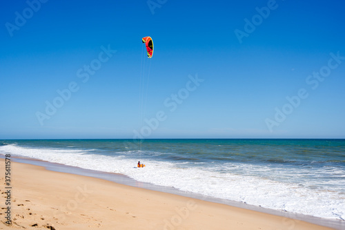 Beautiful kiteboarding surfing with golden sand sea water. Kite in the air on the beach, sunny outdoors background.