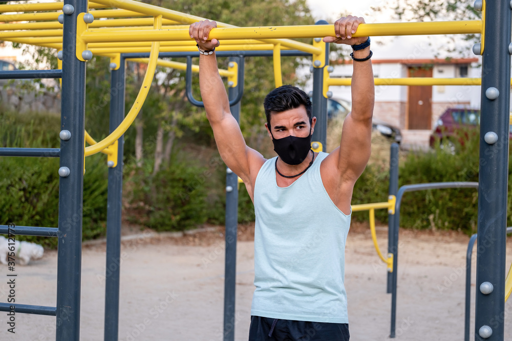 Fototapeta premium Strong young latin man doing calisthenics with facemask
