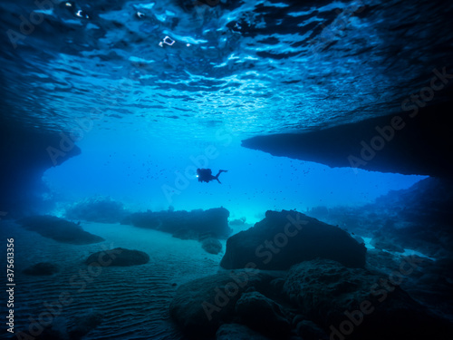 Seascape of coral reef in the Caribbean Sea / Curacao with Diver in cave "Blue Room"