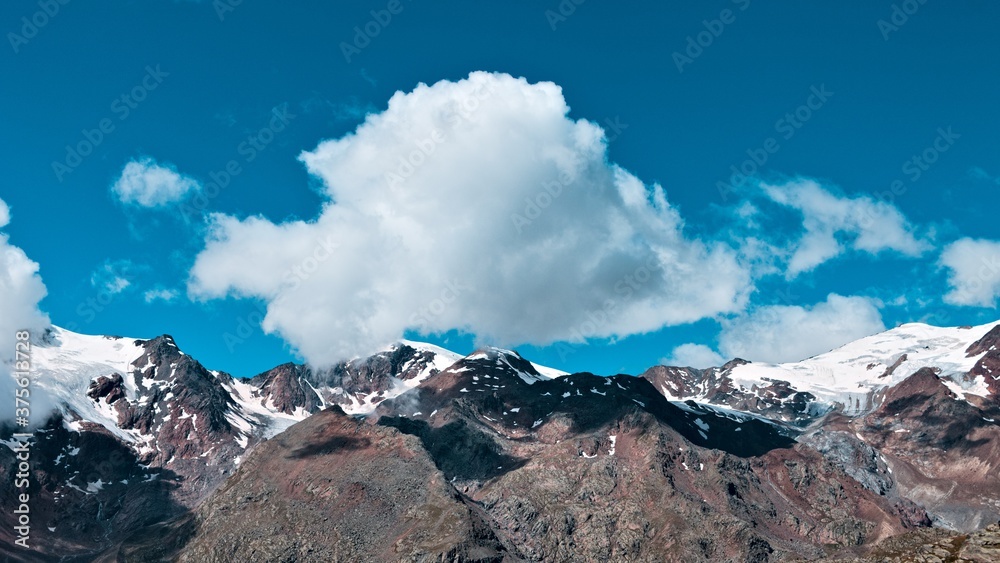 An isolated cloud above the peak of the mountain in the italian alps (Trentino, Italy, Europe)