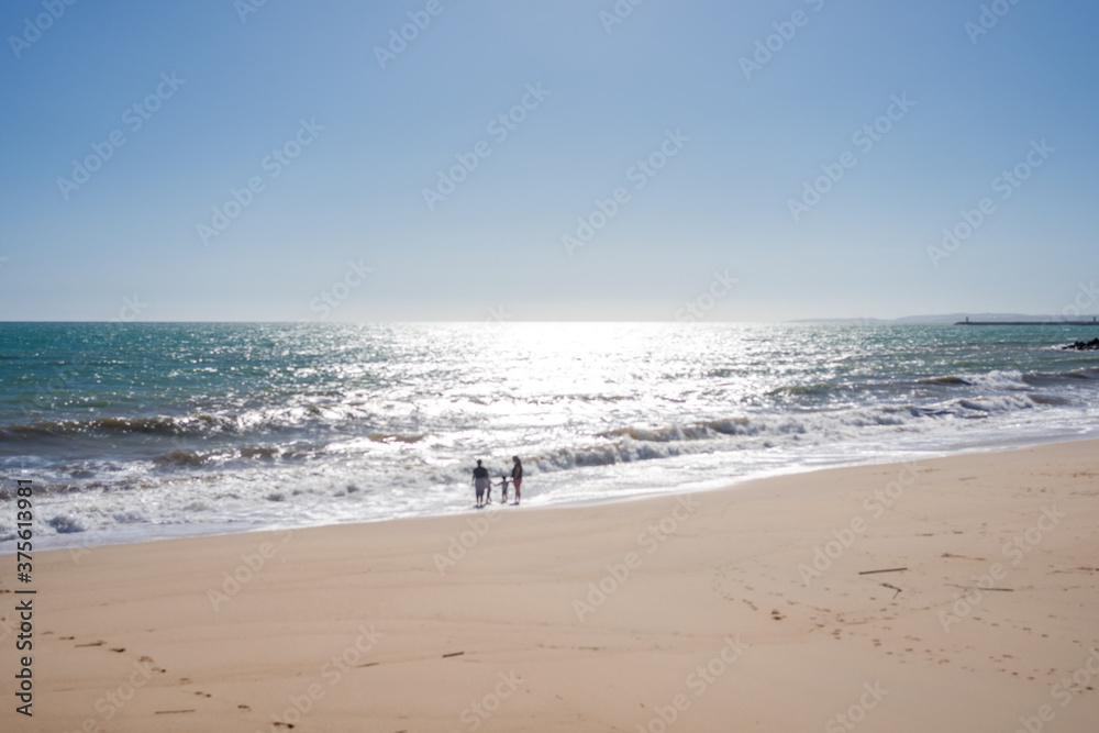 Back view of young family looking to the sea on sunny blue sky outdoors background.