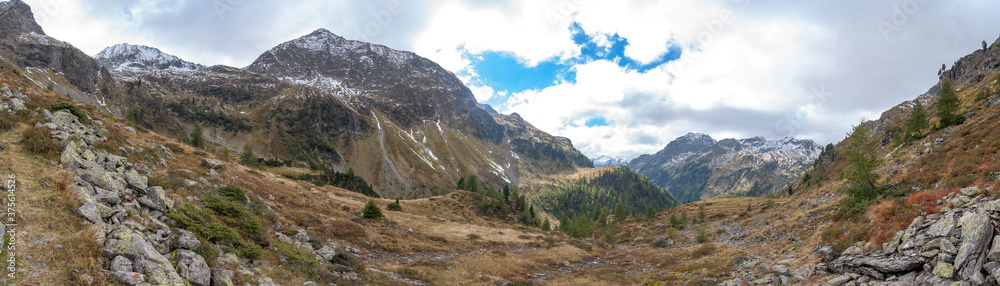 Panoramic view from the Zinkwand in Austria to the surrounding mountain peaks. Autumn mood, there is already snow. The sky is cloudy.