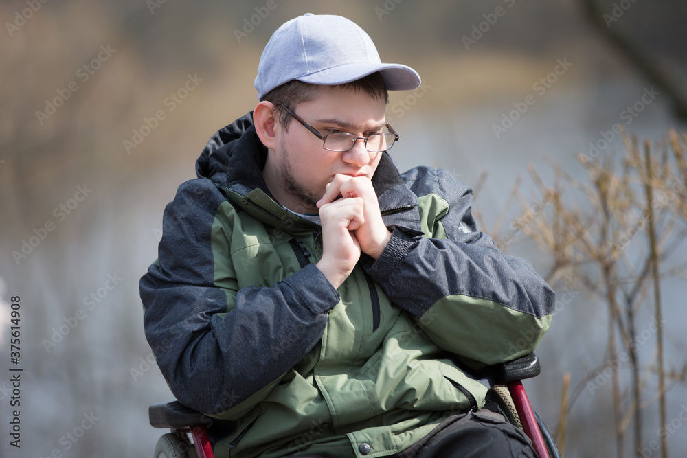 Sad guy in a wheelchair on a walk